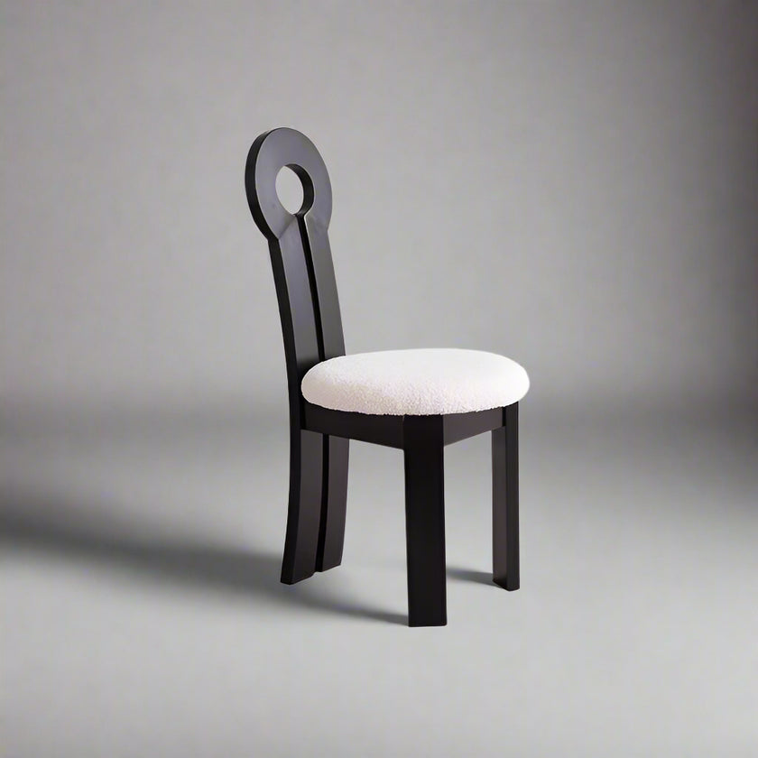 Side angle of Noor chair showing curved wood frame and plush white upholstered seat